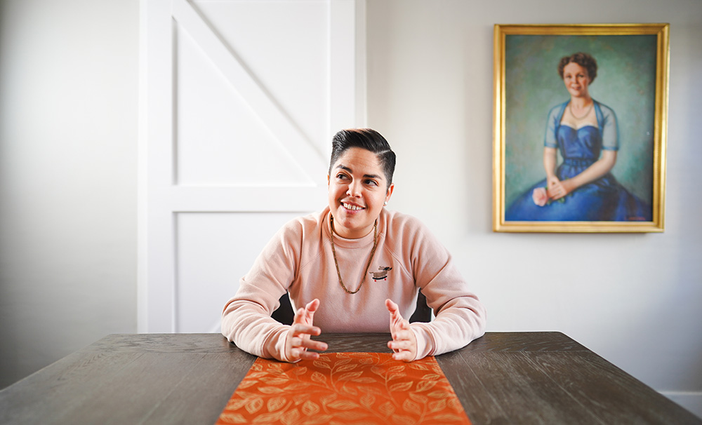 Taylor Scoma - Butch Lesbian with painting of woman behind them