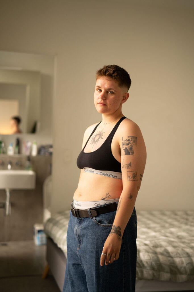 Eli Langfere - Butch lesbian stands in bedroom